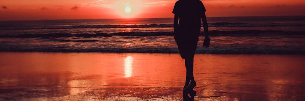 Silhouette of a person meditating against a beautiful sunset sky.